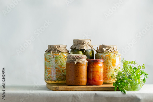 Fermented preserved or canning various vegetables zucchini sauerkraut carrots cucumbers in glass jars on table photo