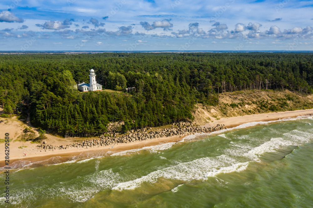 Top view of the sea and the Uzhava lighthouse. Blue sky. Green forest. Top view of the sea and the Uzhava lighthouse. Blue sky. Green forest.