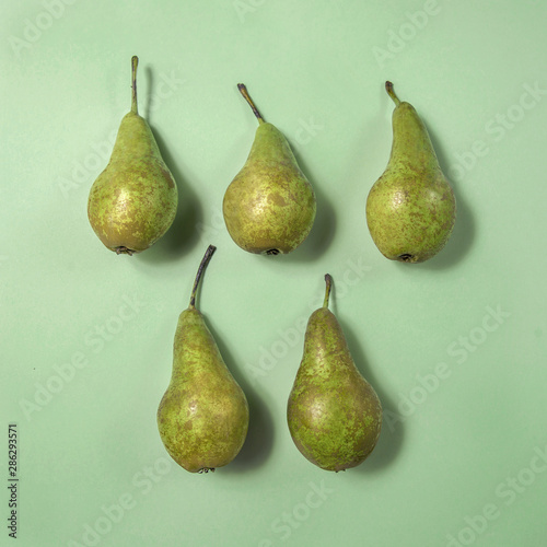 Row of fresh pears on green background. From top view, minimal food concept