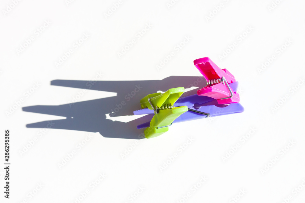 CLOTHING CLAMPS ILLUMINATED BY THE SUN WITH SHADOWS ON WHITE BACKGROUND CLOTHING CLAMPS ILLUMINATED BY THE SUN WITH SHADOWS ON WHITE BACKGROUND