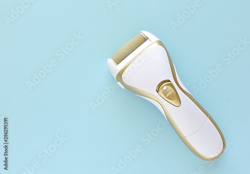 Electric foot care tool, hard skin removal, feet file, top view on blue background