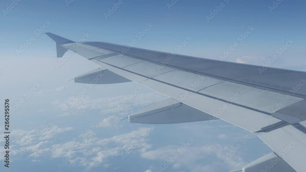 View on blue sky and fluffy white clouds through the window of the aircraft. Scenic view from flying airplane. View on blue sky and fluffy white clouds through the window of the aircraft. Scenic view from flying airplane.