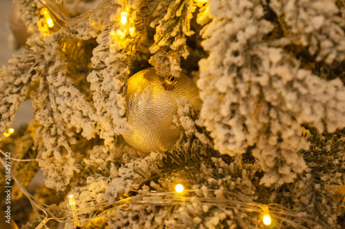 Christmas ball and garland on the Christmas tree. the garland shines with a golden, yellow warm light. Christmas, Christmas background for cards, greetings. © queen1987