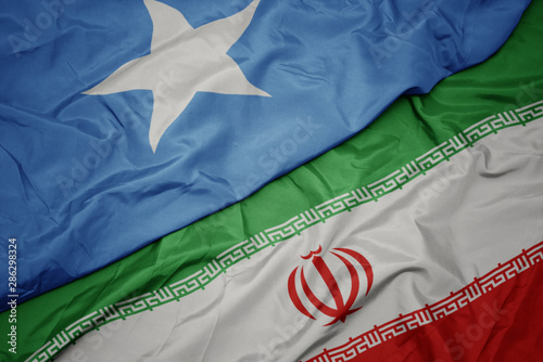 Fotografía waving colorful flag of iran and national flag of somalia.