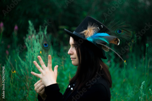 blue-eyed girl in a top hat with a peacock feather
