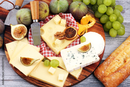 Cheese platter with different cheese and grapes and figs and nuts.