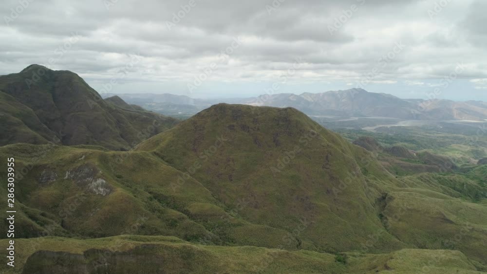 Aerial view of mountains covered with green vegetation, valley, trees in vicinity volcano Pinatubo. Slopes of mountains, sky and clouds. Cordillera region. Luzon, Philippines. Aerial view of mountains covered with green vegetation, valley, trees in vicinity volcano Pinatubo. Slopes of mountains, sky and clouds. Cordillera region. Luzon, Philippines.