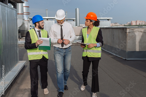 Construction industry group of engineer and architect analyzing the plan of building from the tablet and sheets with a young businessman