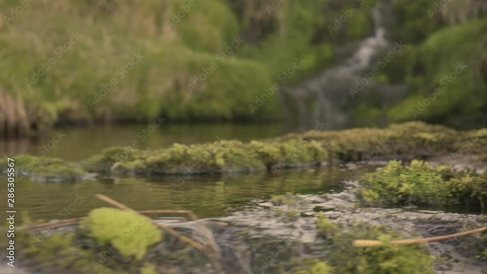 Sliding tracking pull-focus shot of a waterfall from the riverbed Sliding tracking pull-focus shot of a waterfall from the riverbed