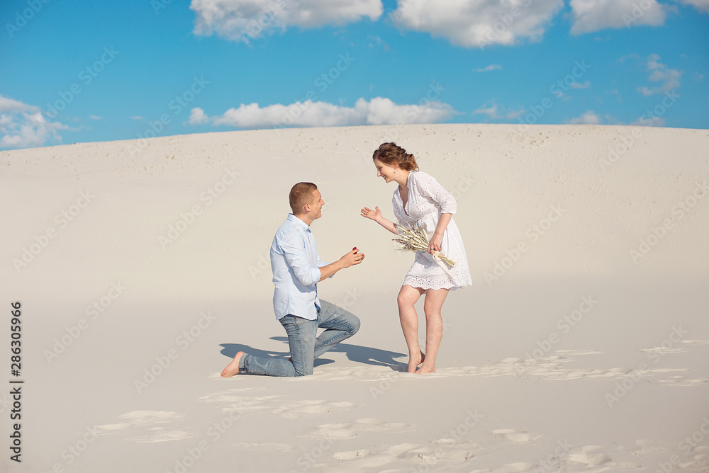 Handsome guy makes the girl a proposal for marriage, bending his knee, standing on the sand in the desert. Happy moments of family life Handsome guy makes the girl a proposal for marriage, bending his knee, standing on the sand in the desert. Happy moments of family life
