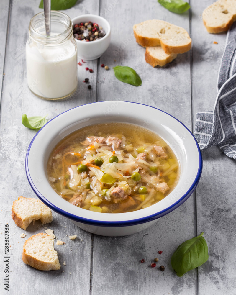 Vegetable soup with cabbage, meat, potatoes, zucchini, carrots, green peas, sour cream and bread. Delicious lunch, traditional first course, Russian Vegetable soup with cabbage, meat, potatoes, zucchini, carrots, green peas, sour cream and bread. Delicious lunch, traditional first course, Russian
