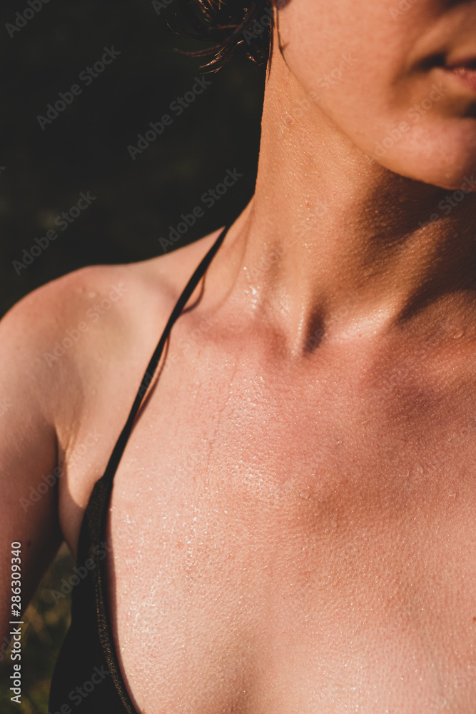Female skin wet and with goosebumps from swimming in cold water. Close-up view of female sitting in the evening sun after taking a swim