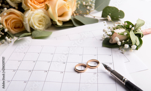 Planning wedding with golden rings on date in calendar photo