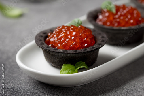 Red caviar in tartlets black, appetizer wine, champagne. Holiday, new year, Christmas, buffet. Delicious canape, food