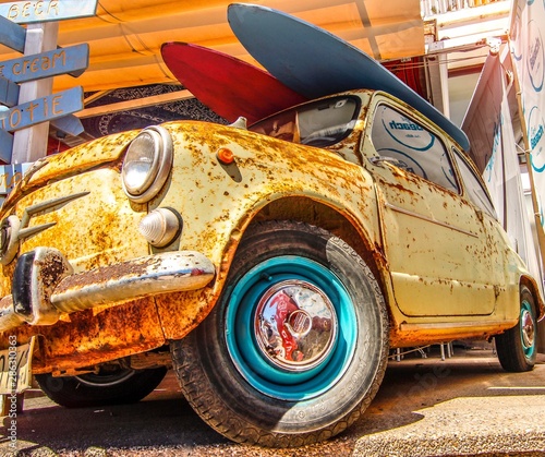 rusty old beach Mini Cooper with surfboards on the roof photo
