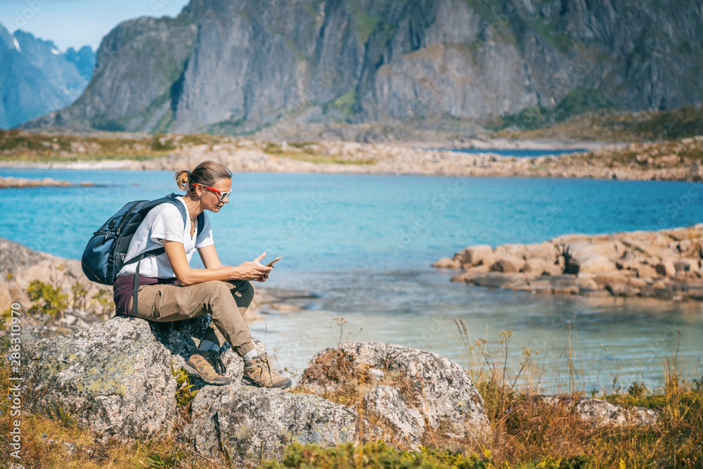 Woman traveler in Norway, on mountains in the Lofoten islands with a phone in his hand exploring the map