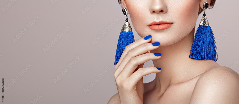 Beautiful woman with large earrings tassels jewelry blue color. Perfect makeup and nails manicure - obrazy, fototapety, plakaty 