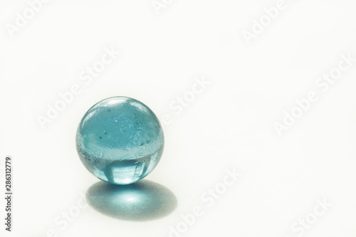 Glass ball of blue color on a white background. Copy space. Abstract background. Shallow depth of field (DOF)