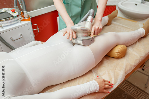 Woman having anti-cellulite lpg massage treatment with apparatus