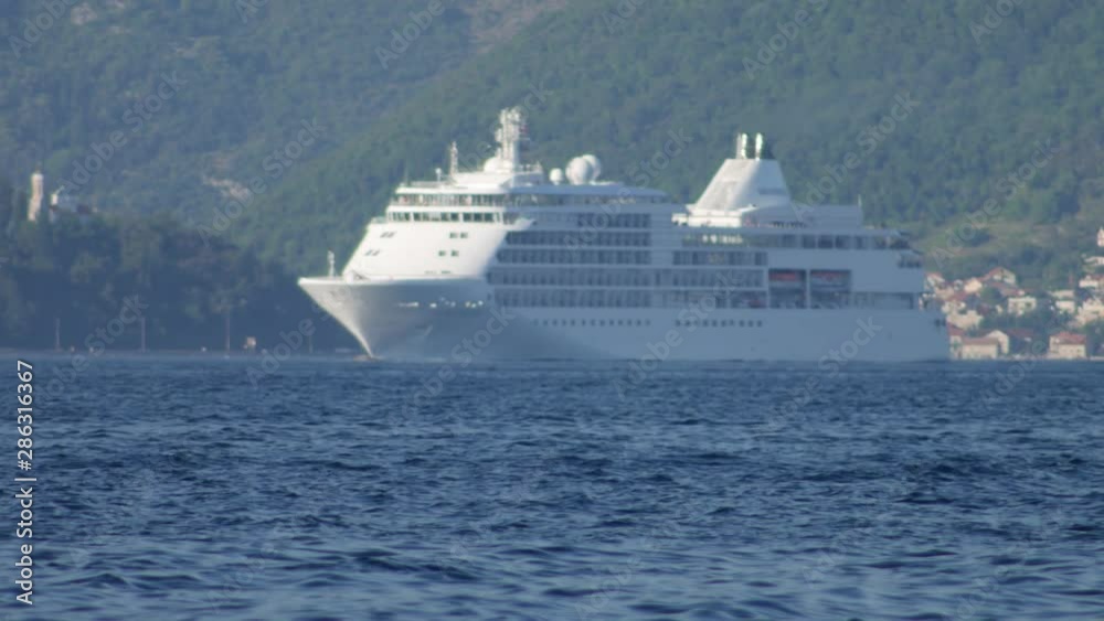 White cruise ship sailing on a sunny day - August 2019, Kotor bay (Boka Kotorska), Montenegro. White cruise ship sailing on a sunny day - August 2019, Kotor bay (Boka Kotorska), Montenegro.