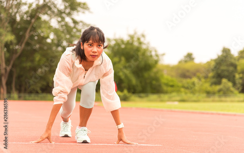 Beautiful Asia woman runner on a race track is ready to run. running or exercising outdoors on the stadium, athletes girl practice on running track in University Stadium. warm up, marathon, Olympic