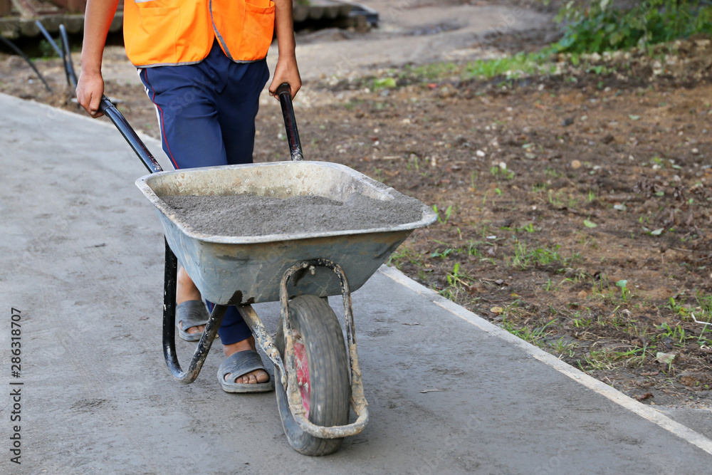 Worker carries a wheelbarrow with the ground. Man with cargo, concept of earthworks, digging, construction of the road, landscaping Worker carries a wheelbarrow with the ground. Man with cargo, concept of earthworks, digging, construction of the road, landscaping