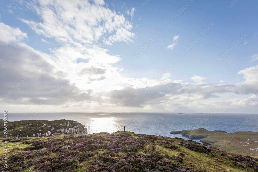 Person standing on cliff edge above the sea on Isle of Skye