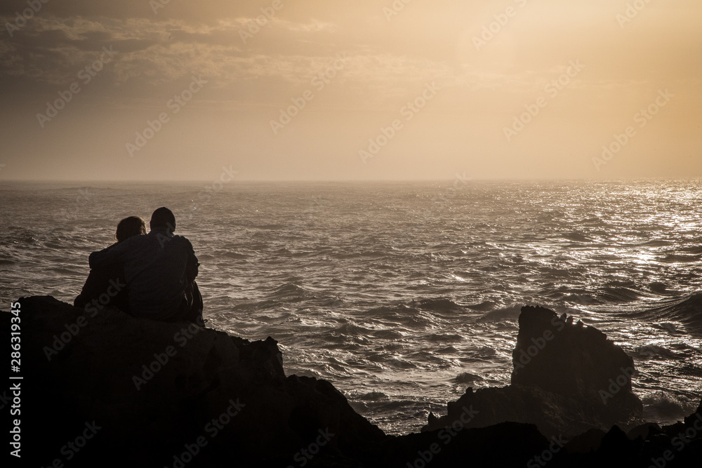 Silhouette of young couple looking at the sea