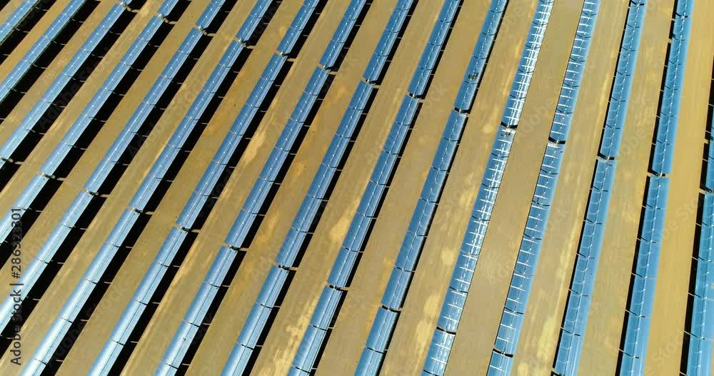 Solar panels in a thermal power plant, photovoltaic power plant. There is the reflection of the sun in the the panels which produce renewable energy, solar energy - aerial view with a drone Solar panels in a thermal power plant, photovoltaic power plant. There is the reflection of the sun in the the panels which produce renewable energy, solar energy - aerial view with a drone