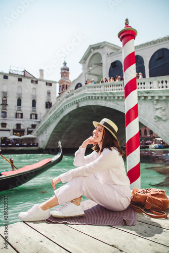 woman sitting near rialto bridge in venice italy looking at grand canal with gondolas © phpetrunina14