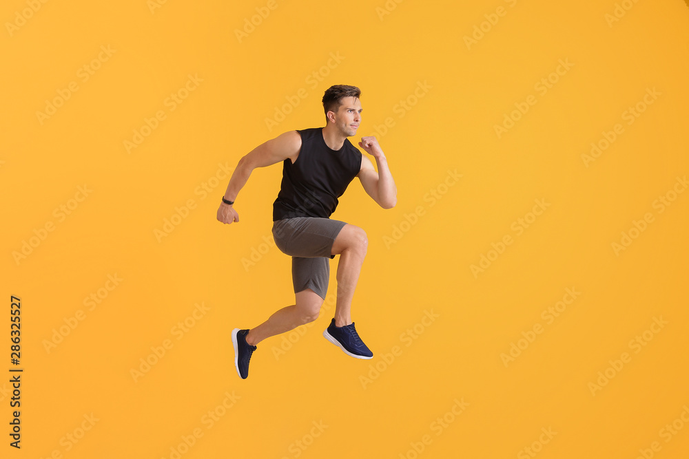 Running young man on color background