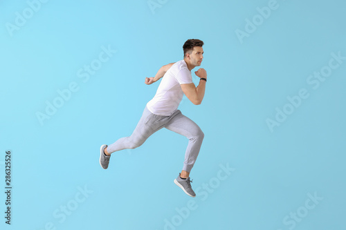 Running young man on color background © Pixel-Shot