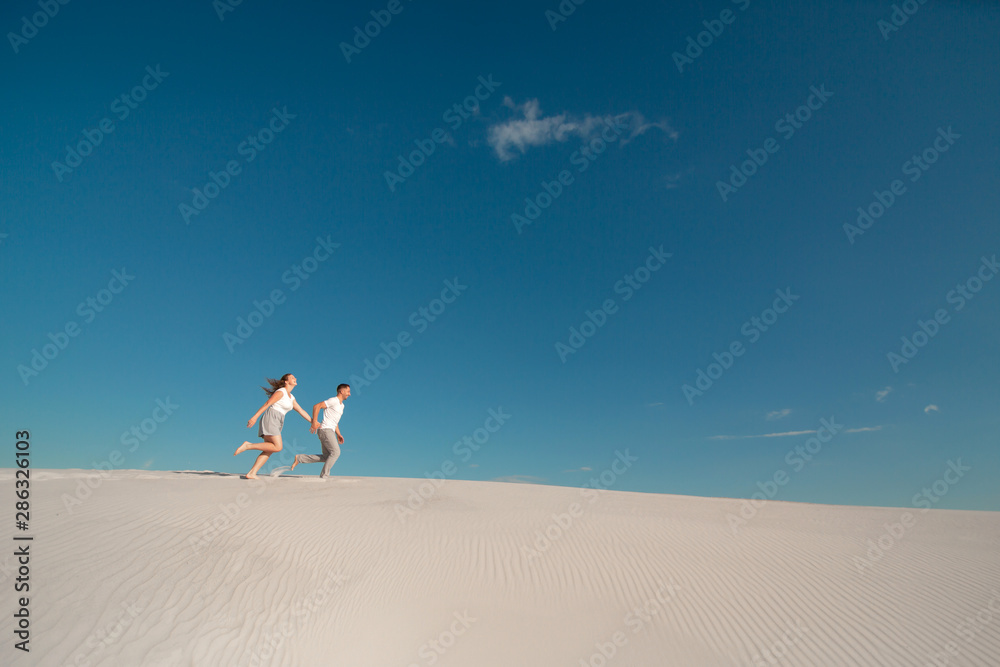Romantic couple in love running on white sand in desert