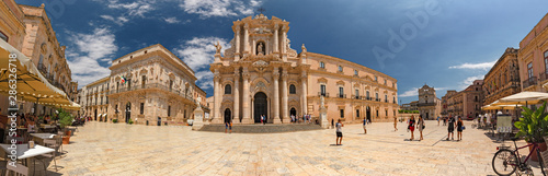 Some tourists are walking admiring the baroque cathedral in the historic center of the island of Ortigia in Syracuse, in Sicily, Italy.