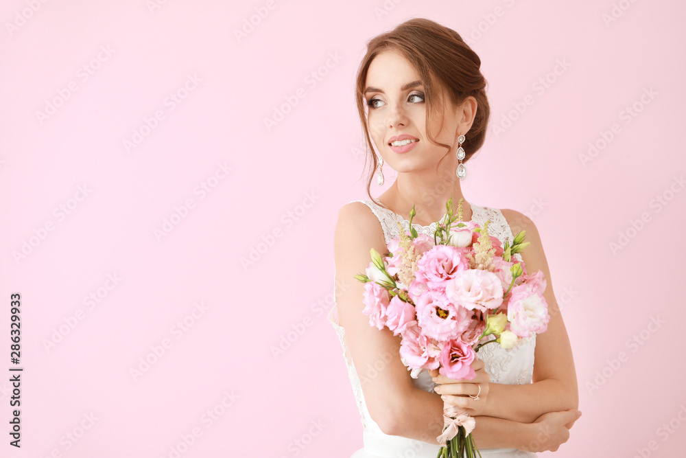 Portrait of beautiful young bride with wedding bouquet on color background