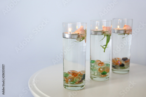 Glasses with water and floating candles on table