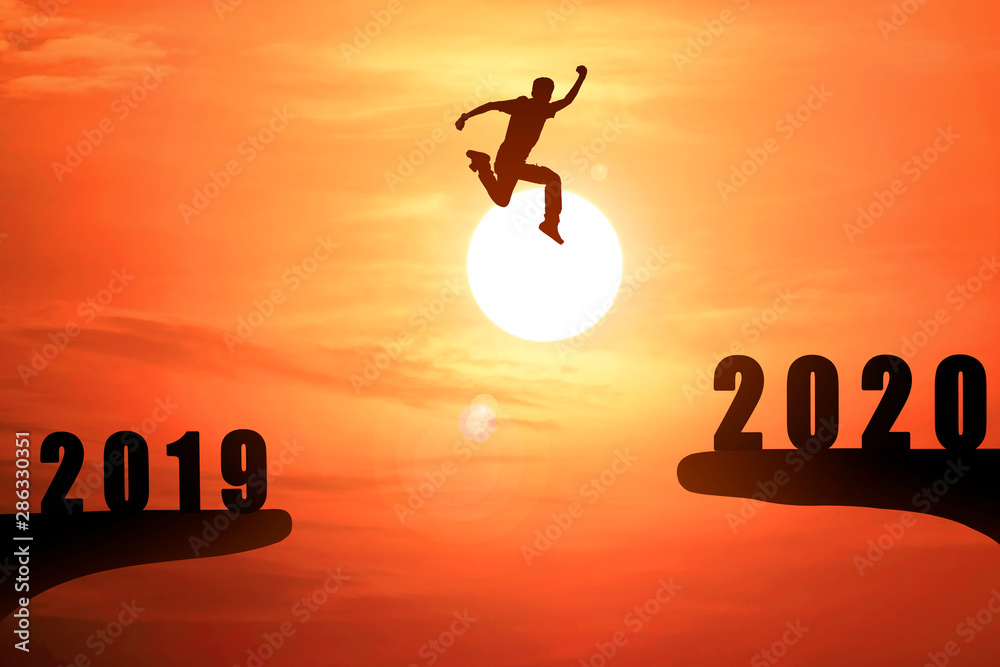 Silhouette of young business man jumping from the cliff that has the year number 2019 to the side that has the year number 2020 with sun rise background, Concept for new year target. Silhouette of young business man jumping from the cliff that has the year number 2019 to the side that has the year number 2020 with sun rise background, Concept for new year target.