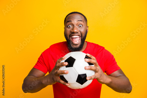 Photo of cute childish rejoicing american man ready to play football while isolated with yellow background © deagreez