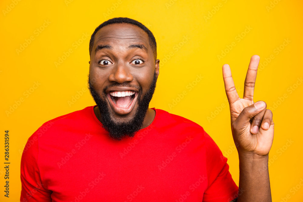 Close up photo of black man rejoicing enjoying showing you v-sign saying hi while isolated with yellow background Close up photo of black man rejoicing enjoying showing you v-sign saying hi while isolated with yellow background
