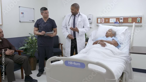 Doctor and nurse reviewing patient info with family with tablet, camera moves photo