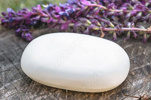 Natural lavender soap with lavender field flowers on a wooden background. Body care.