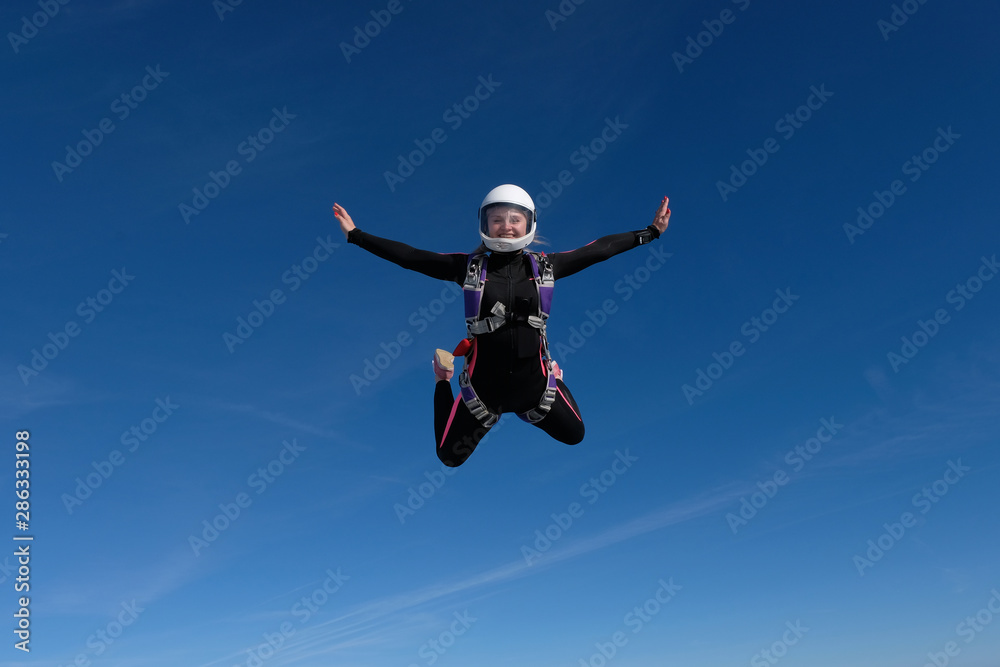Skydiving. Blonde girl is flying in the blue sky. Skydiving. Blonde girl is flying in the blue sky.