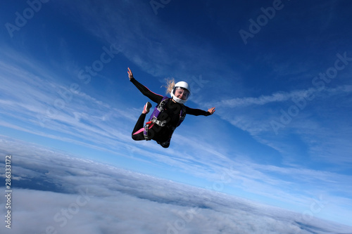 Skydiving. Blonde girl is flying in the blue sky.