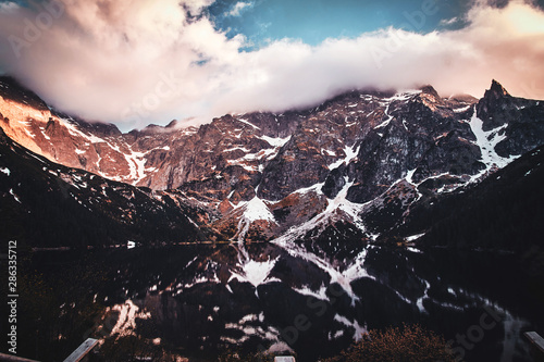 Breathtaking view to the beautiful mountains with mirroed reflection and clouds at sunset time. photo