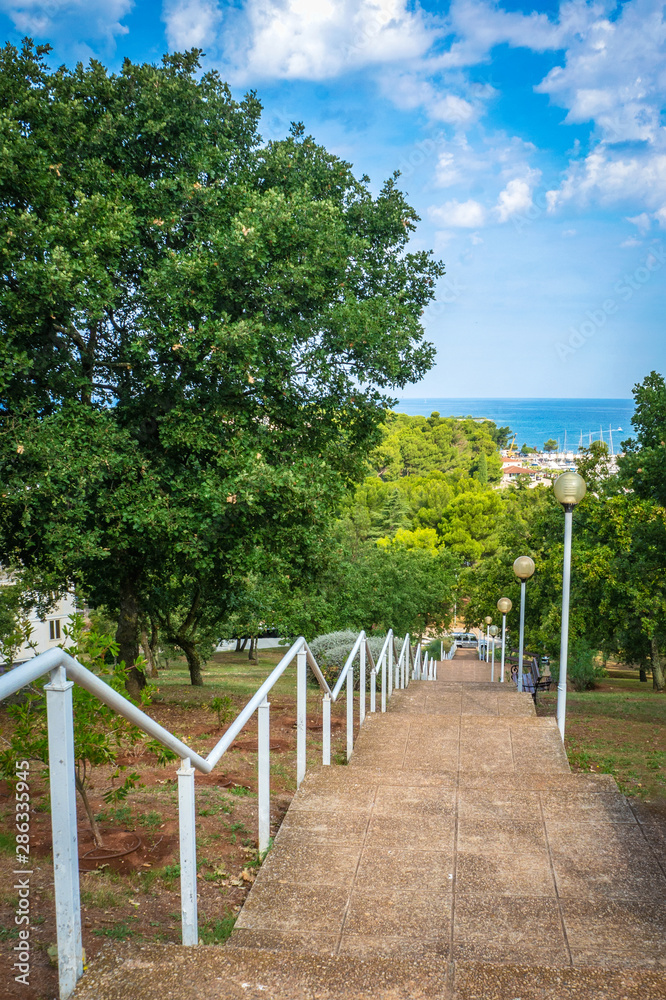 Stone staircase with lanterns and railings down to the sea. Sunny day