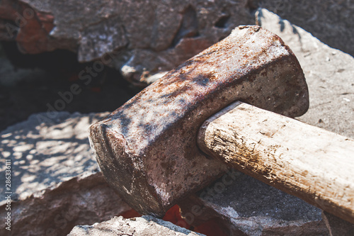 Rusty sledgehammer on broken bricks and concrete stones.