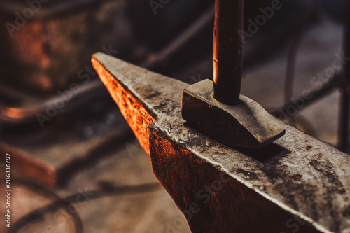Foto Close up photo shoot of hammer and anvil at dark smith workshop.