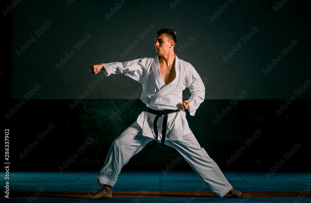 One judoka fighter man in kimono practicing in the gym