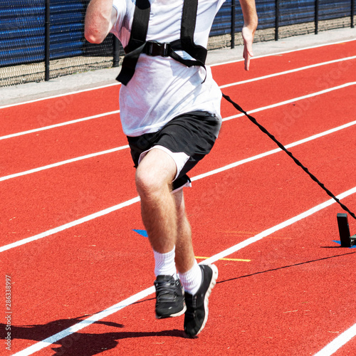Front view of runner pulling weighted sled on a red track