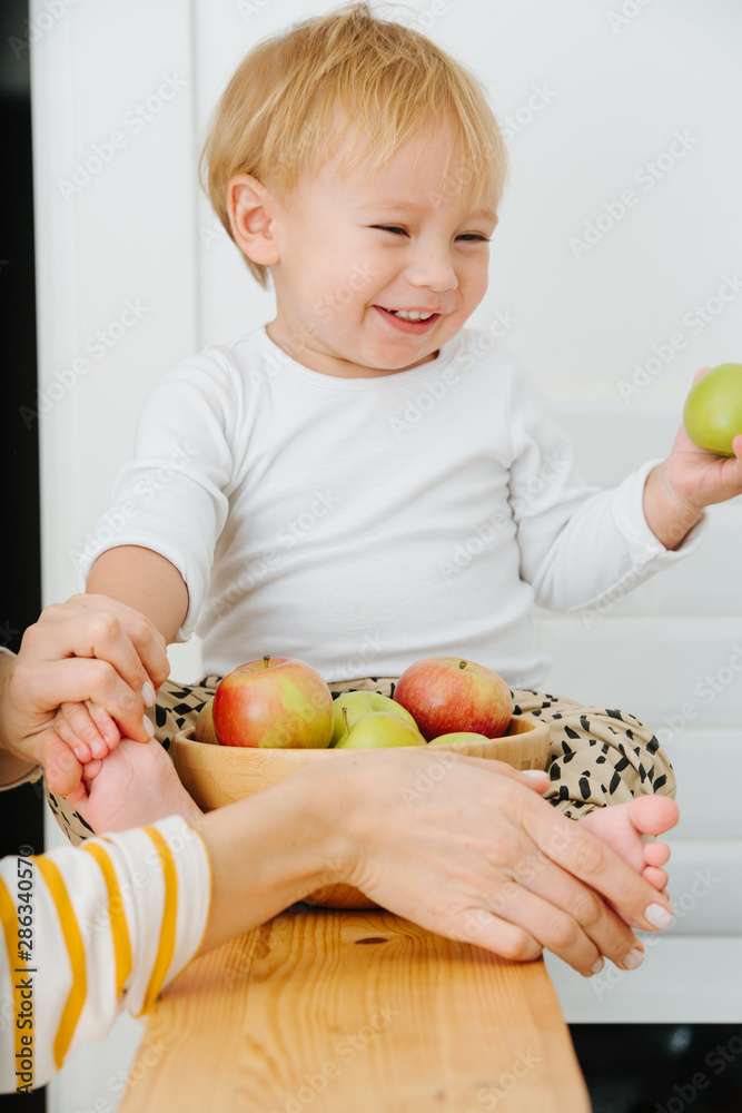 Fototapeta premium lly blond toddler boy is explores, plays with apples from backet.